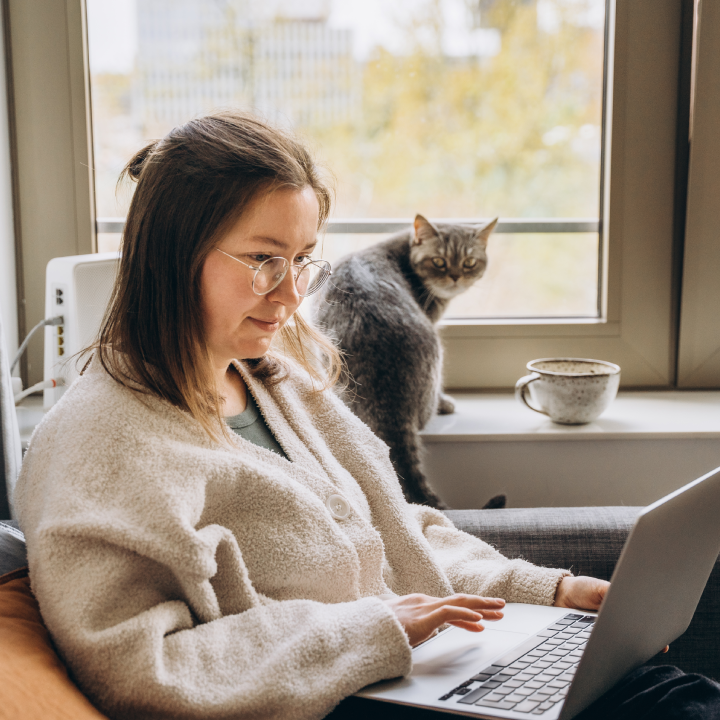 Young woman working at home remotely using a laptop while sitting on the sofa