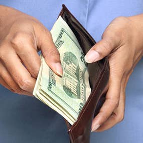 Woman in blue shirt opening wallet © PTstock/Shutterstock.com